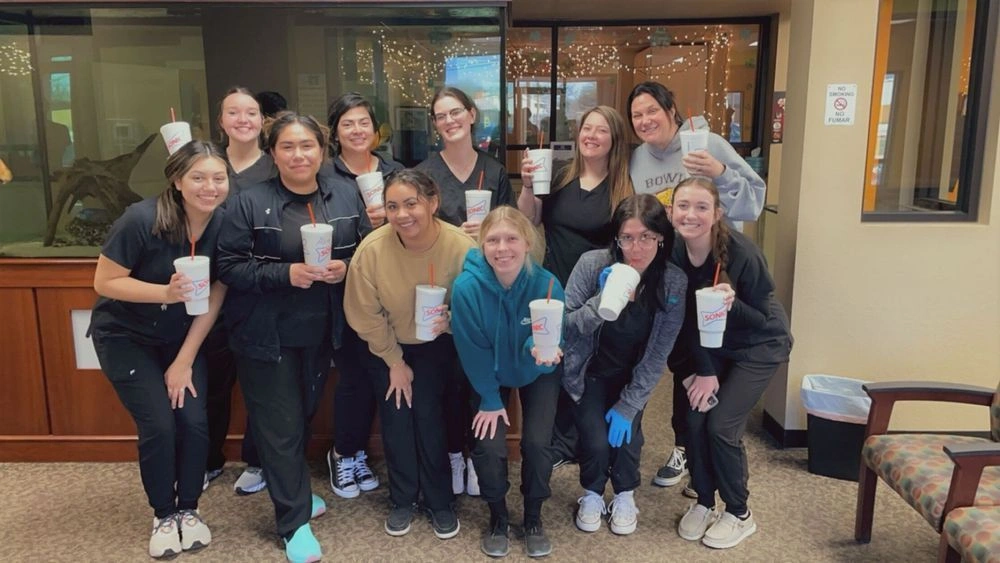 students posing with drink cups in group photo
